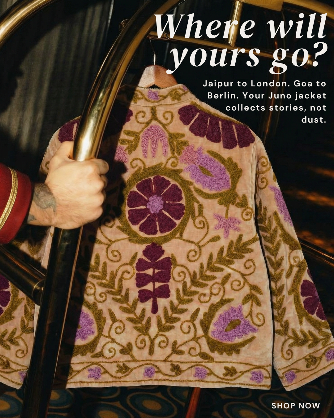 Embroidered jacket with floral patterns held by a person, with promotional text about travel and Juno jackets.